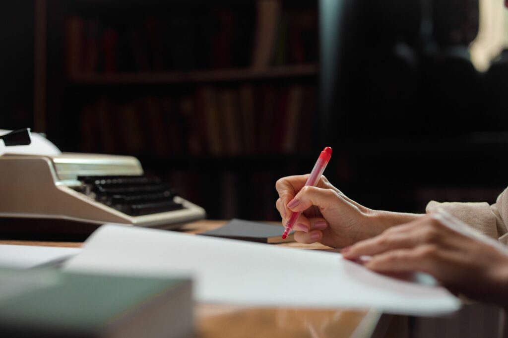 A hand writing with a pen in a cozy library setting with a vintage typewriter, an image for Selective Hadith Use? Do Muslims Reject Only Embarrassing Reports