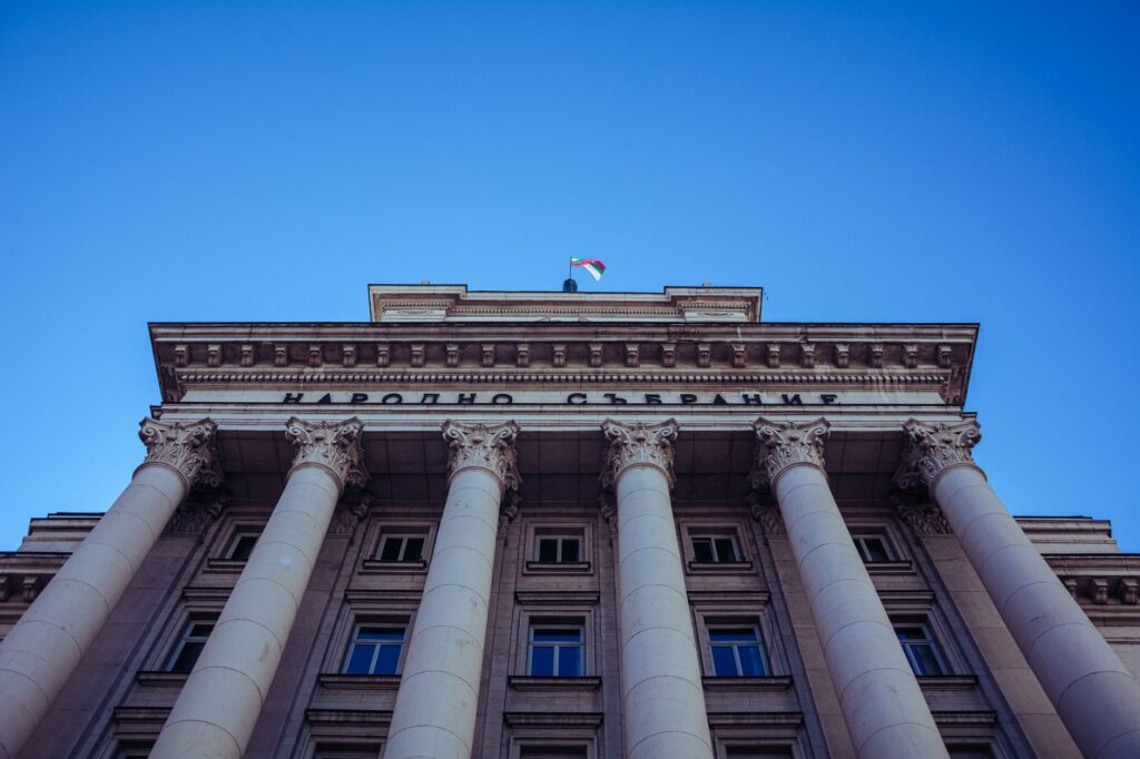 Low-angle view of Sofia's Parliament Building with majestic columns and clear sky, an image for Political Control: Is Religion Just a Tool of Power