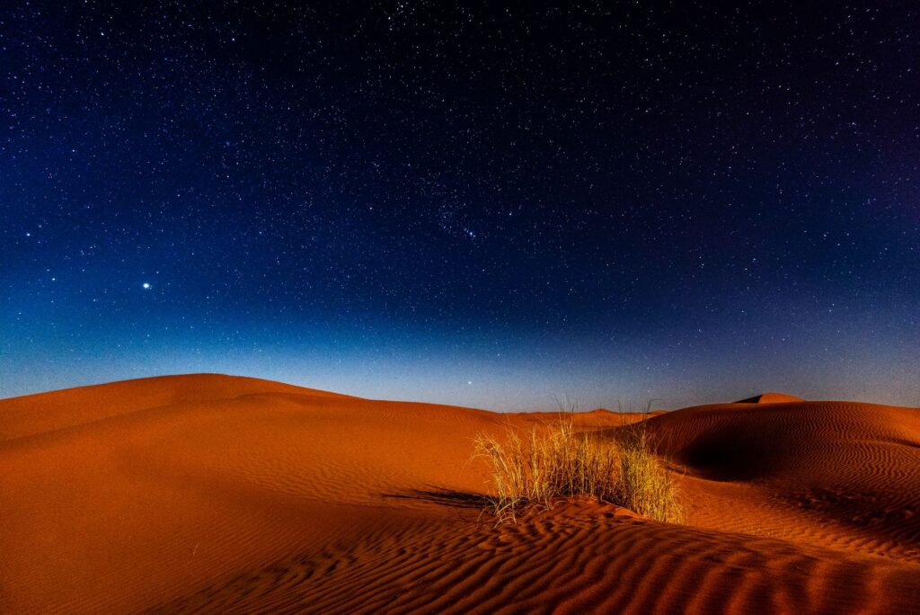 Majestic night sky over sand dunes in Morocco's Zagora Province, highlighting the beauty of nature's tranquility.