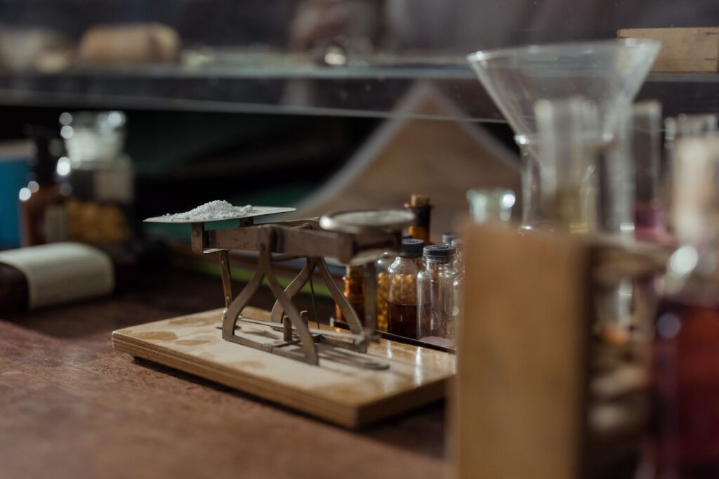 Close-up of an antique apothecary scale with pill bottles in a vintage pharmacy setting.