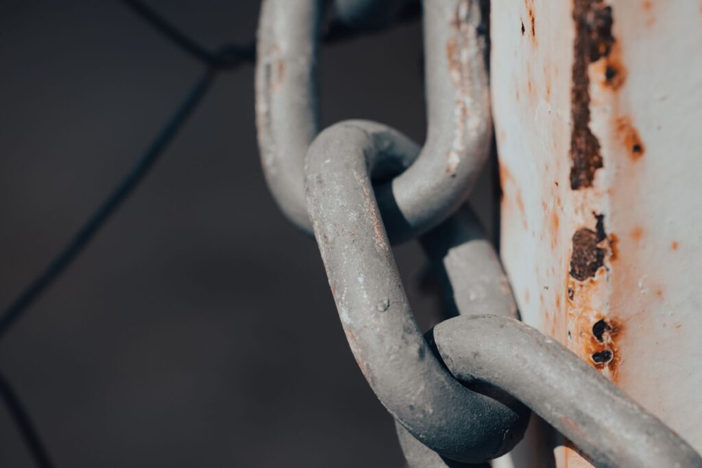Close-up shot of a rusty metal chain wrapped around a weathered post, an image for Slavery in Islamic Sources: The Hardest Question