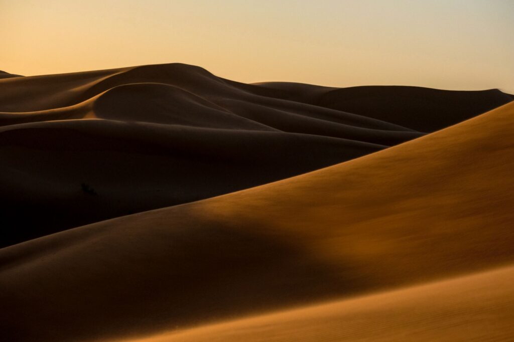 Scenic sunrise over golden sand dunes in Ksar Tanamouste, Morocco.